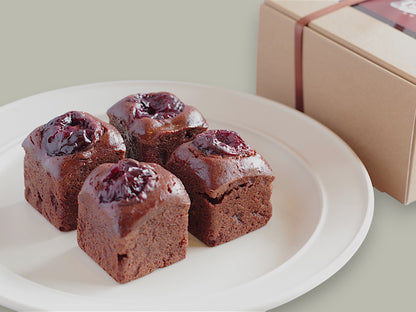 Four CACAOKOBO TRIBUTE カカオ工房トリビュート cherry brownies topped with dark cherries on a white plate with gift box