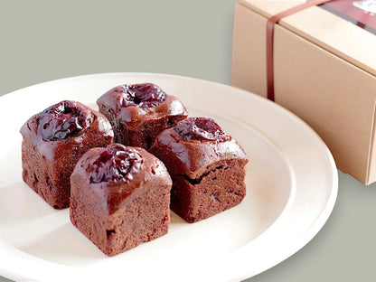 Four CACAOKOBO TRIBUTE カカオ工房トリビュート cherry brownies topped with dark cherries on a white plate with gift box